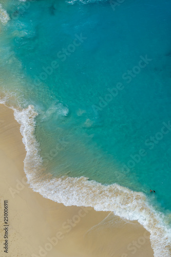 Vertiginous, swirling foamy water waves at the ocean photographed from above cliff.