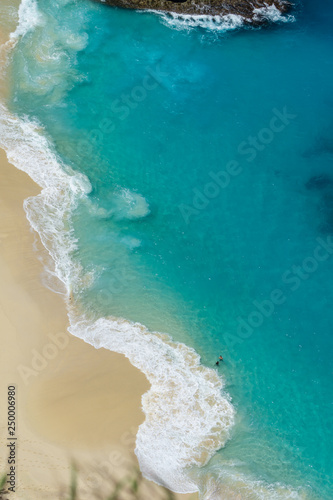 Vertiginous, swirling foamy water waves at the ocean photographed from above cliff.