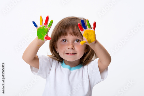 Happy smiling beautiful little girl with her colorful hands in the paint isolated on white background