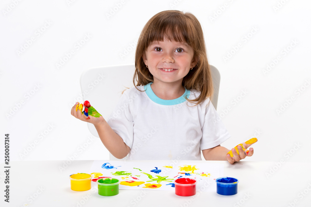 Close-up portrait of a cute cheerful happy smiling little girl draws her own hands with gouache or finger paints isolated on white background Close-up portrait of a cute cheerful happy smiling little girl draws her own hands with gouache or finger paints isolated on white background