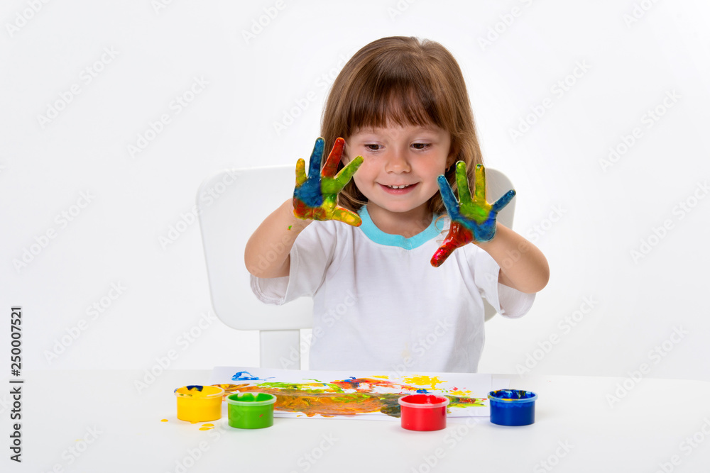 Close-up portrait of a cute cheerful happy smiling little girl draws her own hands with gouache or finger paints isolated on white background Close-up portrait of a cute cheerful happy smiling little girl draws her own hands with gouache or finger paints isolated on white background