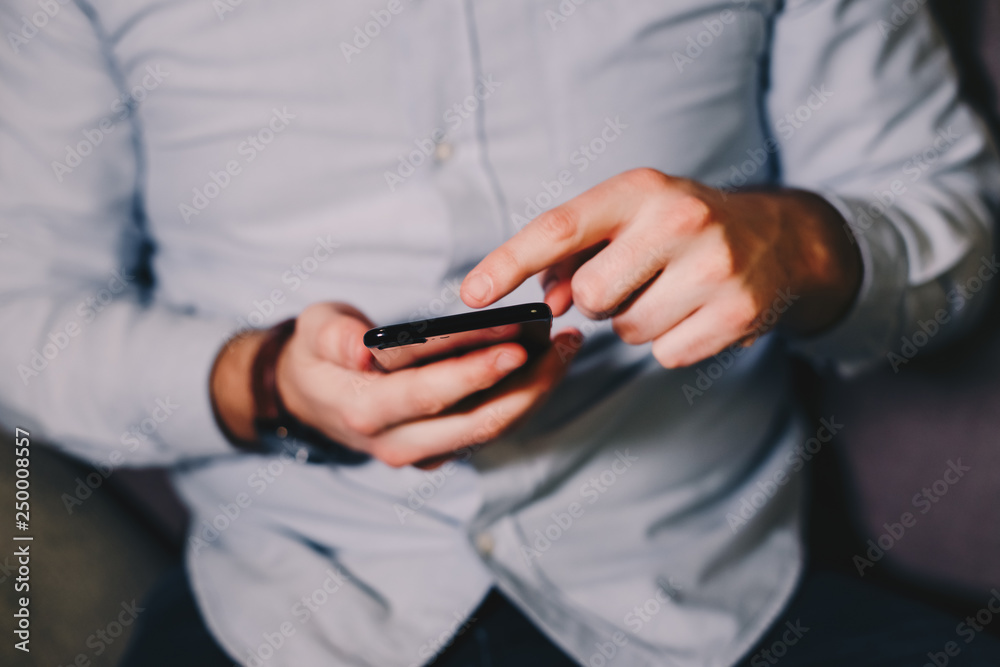 Close up view of male hands using smartphone on the living room couch. Close up view of male hands using smartphone on the living room couch.