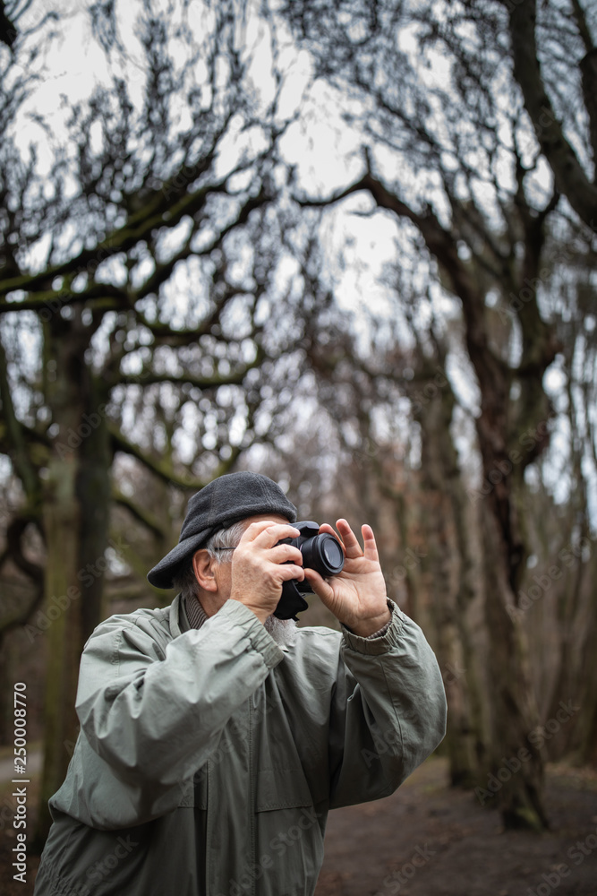 Senior man devoting time to his favorite hobby - photography - taking photos outdoor with his digital camera/DSLR Senior man devoting time to his favorite hobby - photography - taking photos outdoor with his digital camera/DSLR