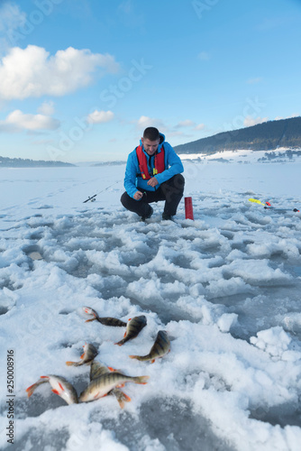 Fisherman catching fish on a frozen lake on the snow. Ice fishing. Selective focus