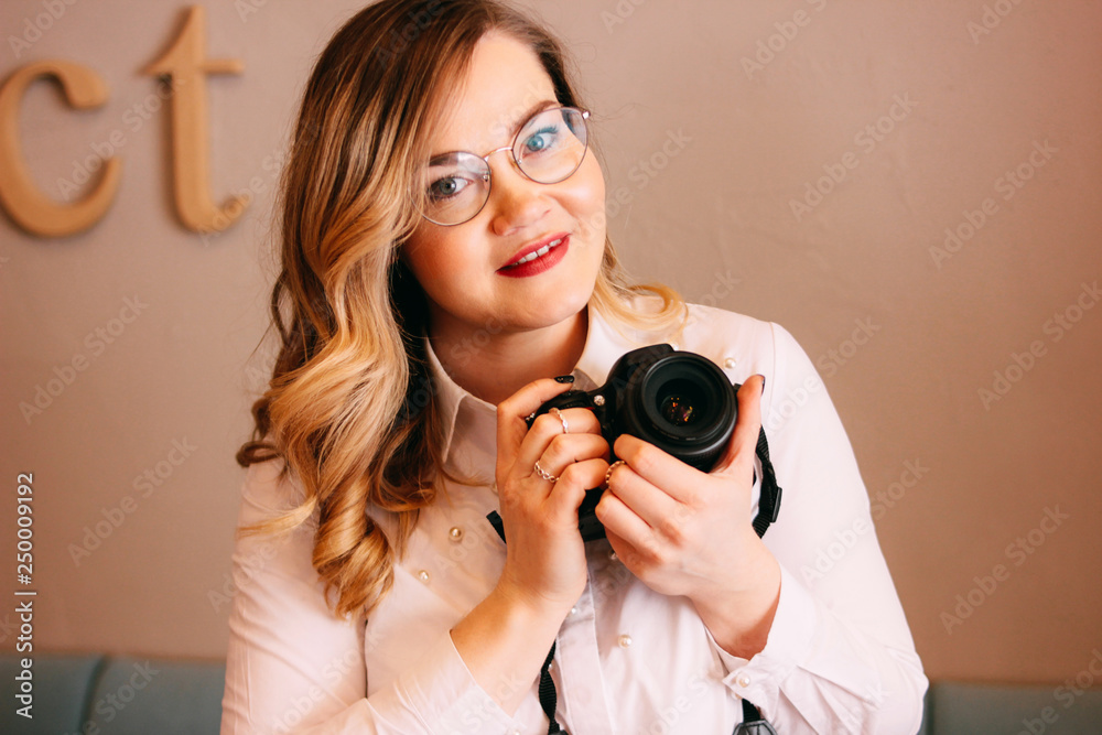 Candid portrait of beautiful blonde girl woman photographer with her camera at work