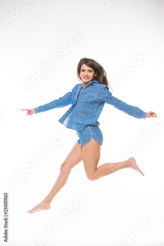 Happy young woman in pajamas jumping isolated on white background