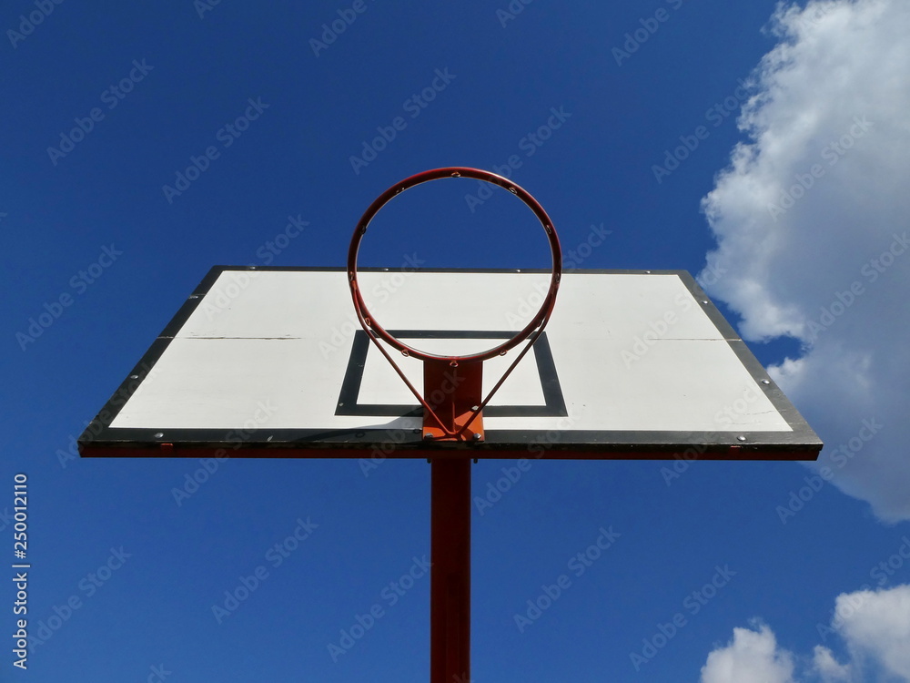 Basketball hoop on an outdoor court with sky and clouds