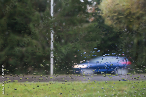 Wallpaper Mural Rain drops on car glass, focus on raindrops. View to the street and car in motion. Long exposure photo. Torontodigital.ca