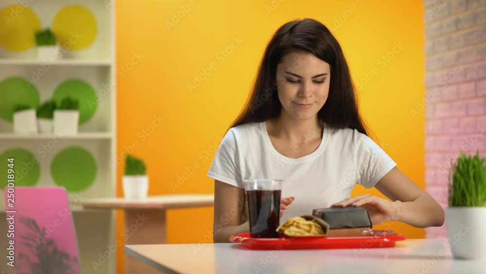 Hungry lady enjoying hamburger taste, dinner in fast food restaurant, appetite Hungry lady enjoying hamburger taste, dinner in fast food restaurant, appetite