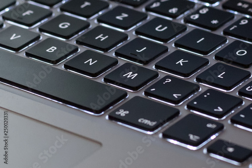 Detail of the silver backlit keyboard with black low keys and touchpad.