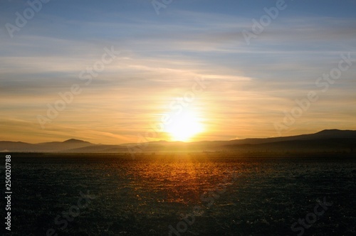Spectacular golden sunrise on cleaned agricultural field with smooth hills on horizon in Khakassia, Russia