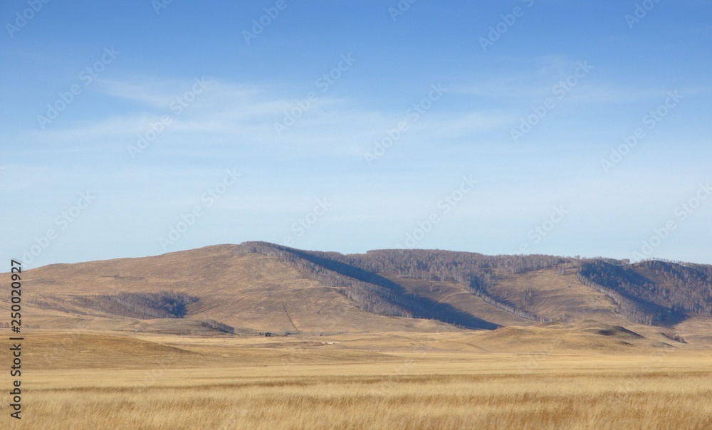 Smooth hills covered with dry grass on horizon with blue sky in Khakassia, Russia Smooth hills covered with dry grass on horizon with blue sky in Khakassia, Russia