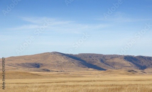 Smooth hills covered with dry grass on horizon with blue sky in Khakassia, Russia © Denis Privalikhin