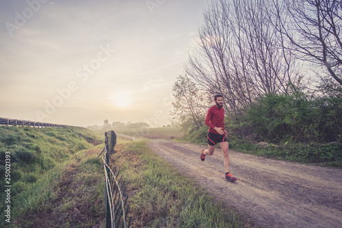 Uomo che corre su una strada di campagna all'alba