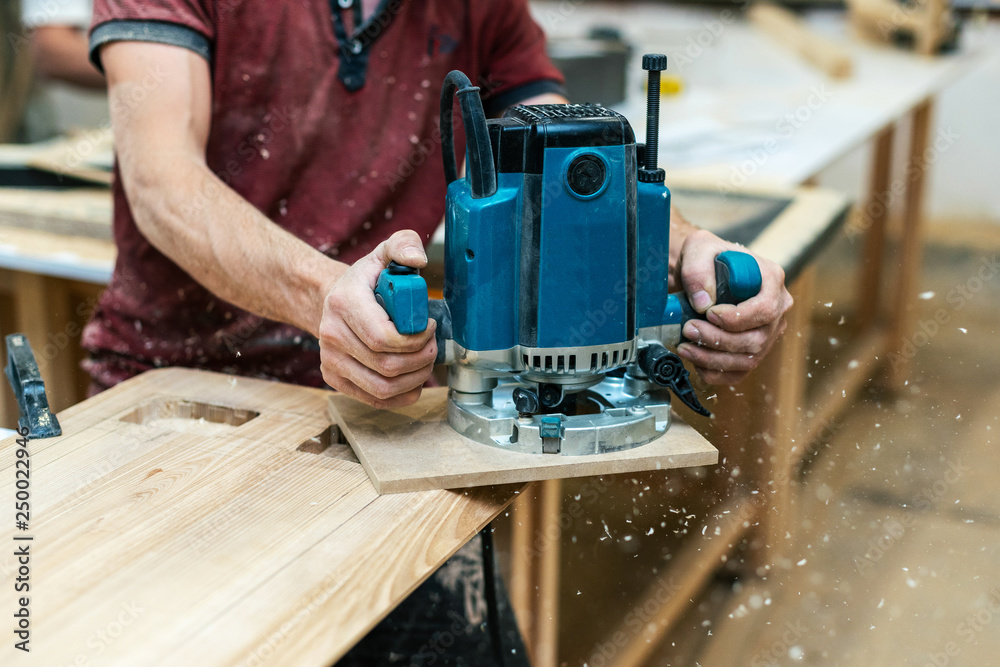 Manual wood concept. Cropped photo of cabinetmaker handyman stand half turn to camera hold electric tool in hand make furniture in garage work shop or workroom