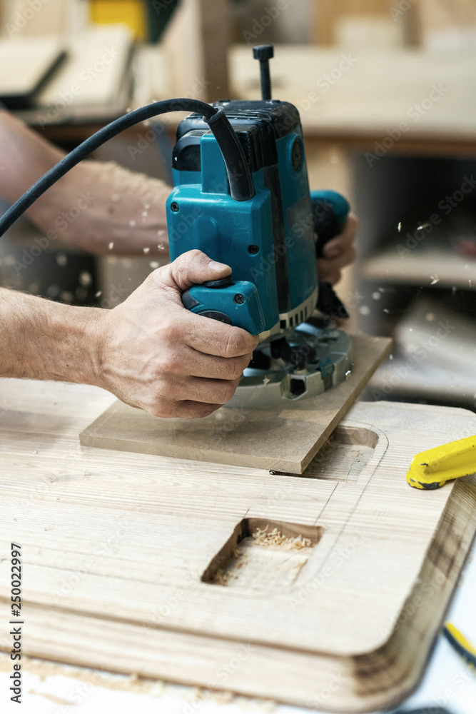 Hobby wood concept. Vertical cropped photo of cabinetmaker handcraft hands hold tool plunge it in wood make furniture in garage or workroom