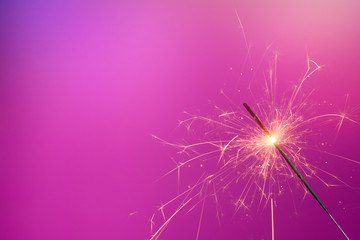 Sparkler on pink background. Shiny bengal fire with copy-space.