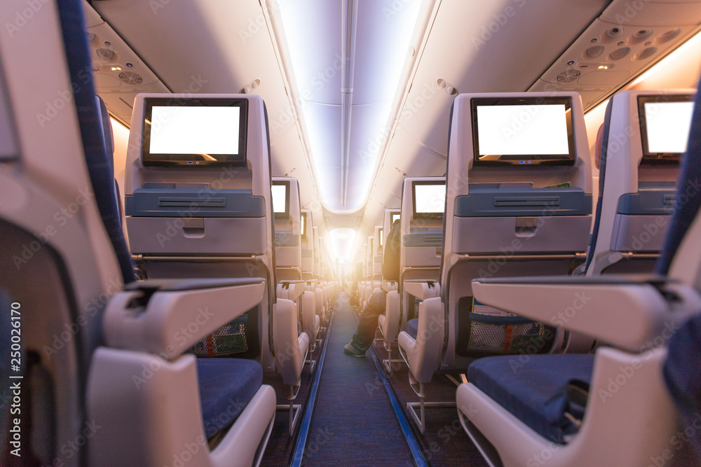 Comfortable seats in cabin of commercial aircraft with screens in chairs back Comfortable seats in cabin of commercial aircraft with screens in chairs back