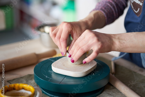 Woman making pottery, hands closeup, blurred background, focus on potters, palms with pottery