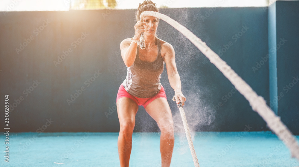 Fit woman with battle rope in functional training fitness gym - Female  athlete doing workout session inside