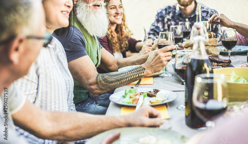 Happy family eating and drinking wine at barbecue dinner on patio outdoor