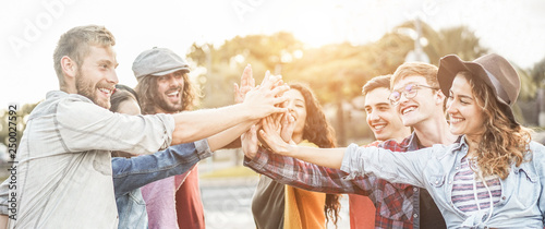 Young millennials friends stacking hands together - Happy students celebrating together - Youth lifestyle, university, social trends, relationship and friendship concept - Focus on hands
