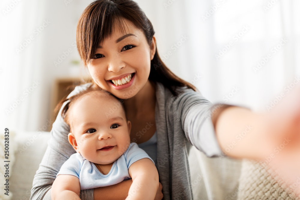 family and motherhood concept - happy young asian mother with little baby son taking selfie family and motherhood concept - happy young asian mother with little baby son taking selfie