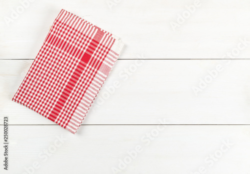 Red checkered dishcloth on white wooden plank table flat lay top view from above