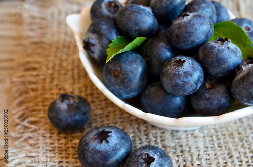 Freshly picked organic blueberries in a white bowl on a burlap cloth background. Blueberry. Bilberries.Healthy eating,vegan food or diet concept.Selective focus.