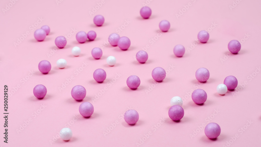 Pink and white small balls are scattered on the pink surface