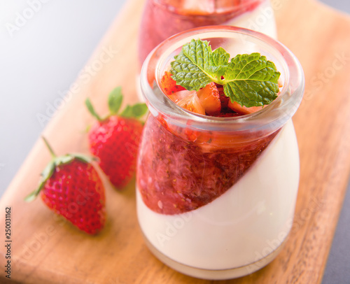Delicous and nutritious double color (colour) strawberry desserts with mint and diced sarcocarp topping isolated with airy blue background, copy space, close up