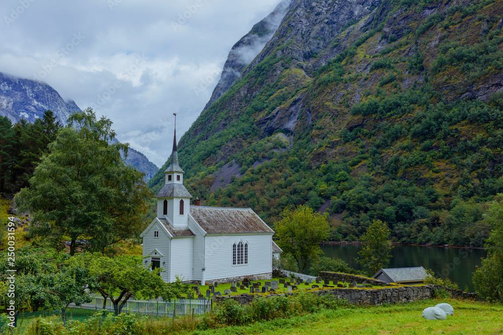 Church with a cemetery stands on the shore of the fjord, Norway