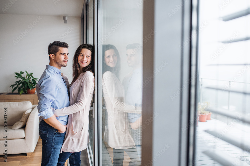 Young couple in love standing by the window at home, hugging. Copy space. Young couple in love standing by the window at home, hugging. Copy space.