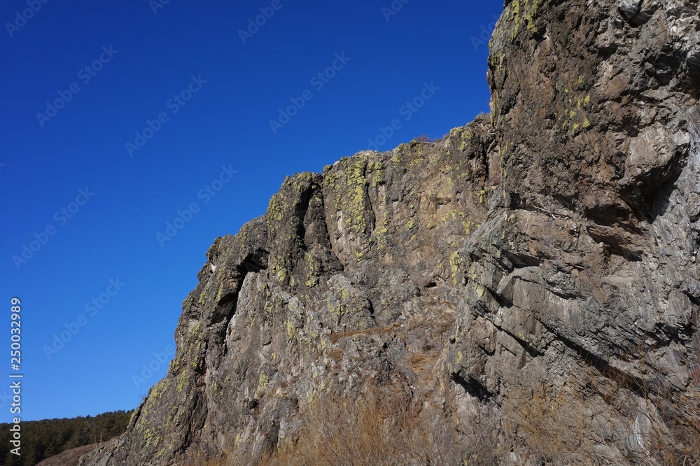 Mountain cliffs on the bank of the river against the blue sky Mountain cliffs on the bank of the river against the blue sky