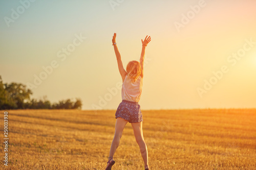 Cute young woman jumping in a wheat field.