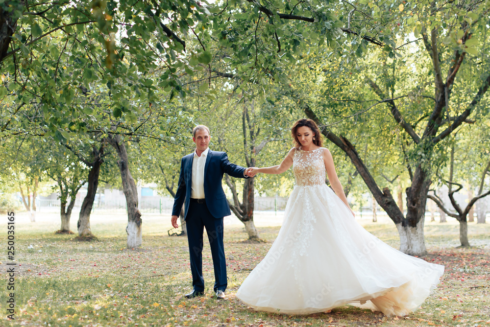 young bride and groom walking in a summer Park with green trees
