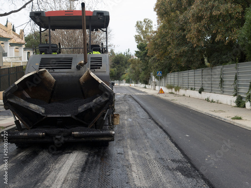 Máquina moderna pesada de asfaltar que extiende y presiona el asfalto caliente. Máquina de reparación de carreteras. Reparación de carretera en ciudad moderna, antes de pasar otra máquina apisonadora.