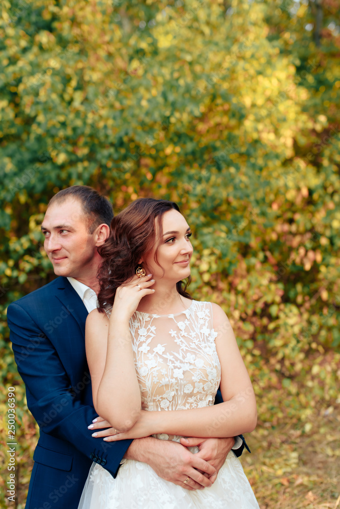 young bride and groom walking in autumn Park with yellow leaves young bride and groom walking in autumn Park with yellow leaves