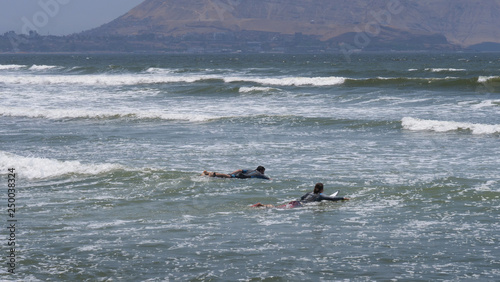 Miraflores Peru. Lima. Coast. ocean surfing waves. Going surfing. Pedling on surfboard. Surfers.  photo