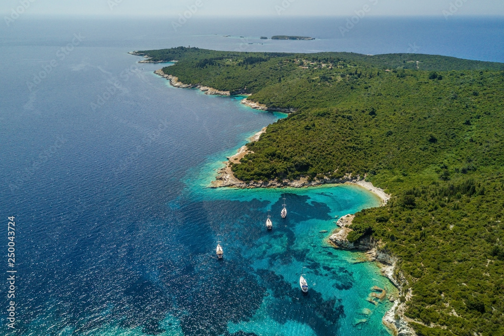 Anchored sailing boats in the small bay from bird view, rocks on the coast, shallow transparent water Anchored sailing boats in the small bay from bird view, rocks on the coast, shallow transparent water