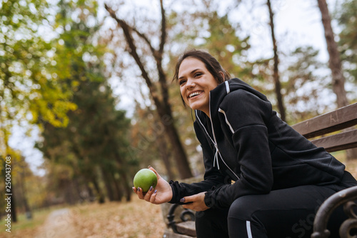 Woman taking break from exercising, sitting on bench and eating apple © cherryandbees