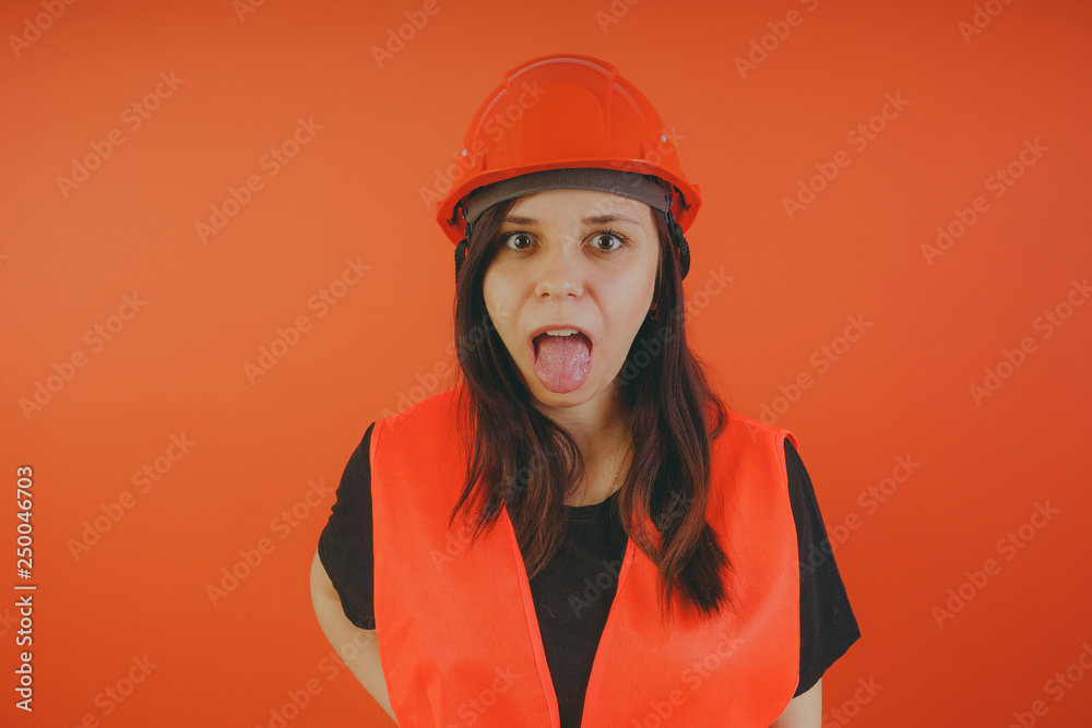 Girl construction worker, road worker or longshoreman, a woman in a helmet and orange vest Girl construction worker, road worker or longshoreman, a woman in a helmet and orange vest