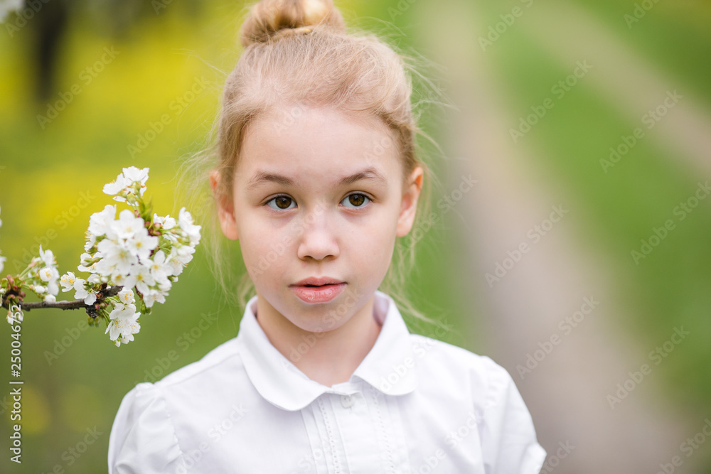 Portrait of a blonde girl near the branch of white blossom cherry in the flowering garden Portrait of a blonde girl near the branch of white blossom cherry in the flowering garden