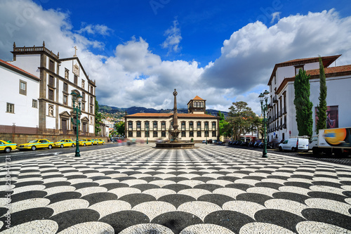 Beautiful cityscape of the townsquare Praca do Municipio in Funchal, Madeira, with the Church of St. John the Evangelist and the city hall, on a summer day with blue sky and clouds photo