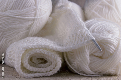 Part of a knitted scarf of white wool and knitting yarn close-up. Knitting is a hobby. Knitting texture © Julia