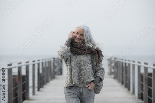 happy mature woman with long grey hair on a pier