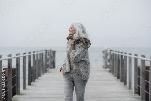mature woman with long grey hair on a pier