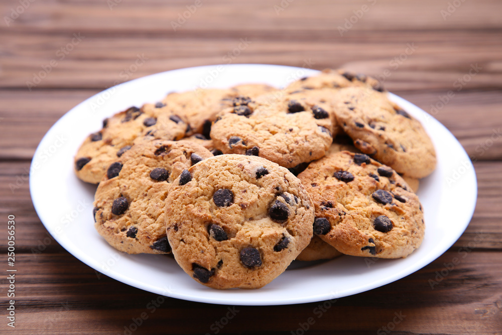 Chocolate chip cookies on plate on brown wooden background Chocolate chip cookies on plate on brown wooden background