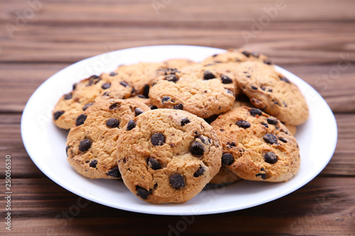 Chocolate chip cookies on plate on brown wooden background