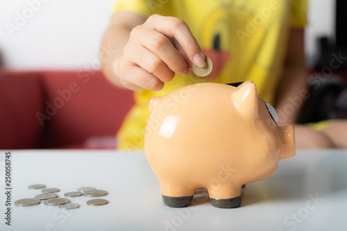 Close up woman hand putting coins into piggy bank